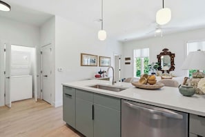 Eine moderne Küche mit einer zentralen Kochinsel, einem integrierten Geschirrspüler und einem Deckenventilator.