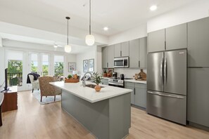 Una cocina moderna con una isla central, electrodomésticos de acero inoxidable y vistas al exterior.