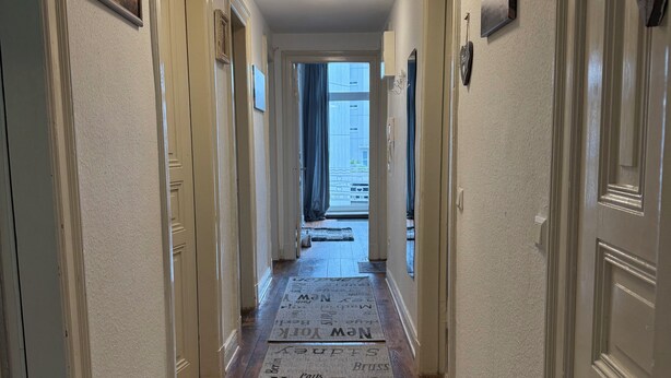 A hallway with a word carpet featuring city names, white walls, and wooden flooring. - 4-room apartment in Cuxhaven on the dyke (Cuxhaven)