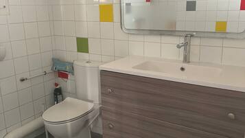 A bathroom with a toilet, sink, mirror, and wooden vanity.