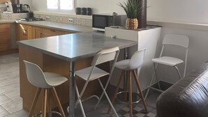 A modern kitchen with a central island, bar stools, and a dining area with a sofa. - Country house (Malataverne)