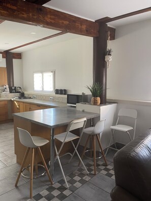 Una cocina moderna con una isla central, taburetes de bar y un área de comedor con un sofá.