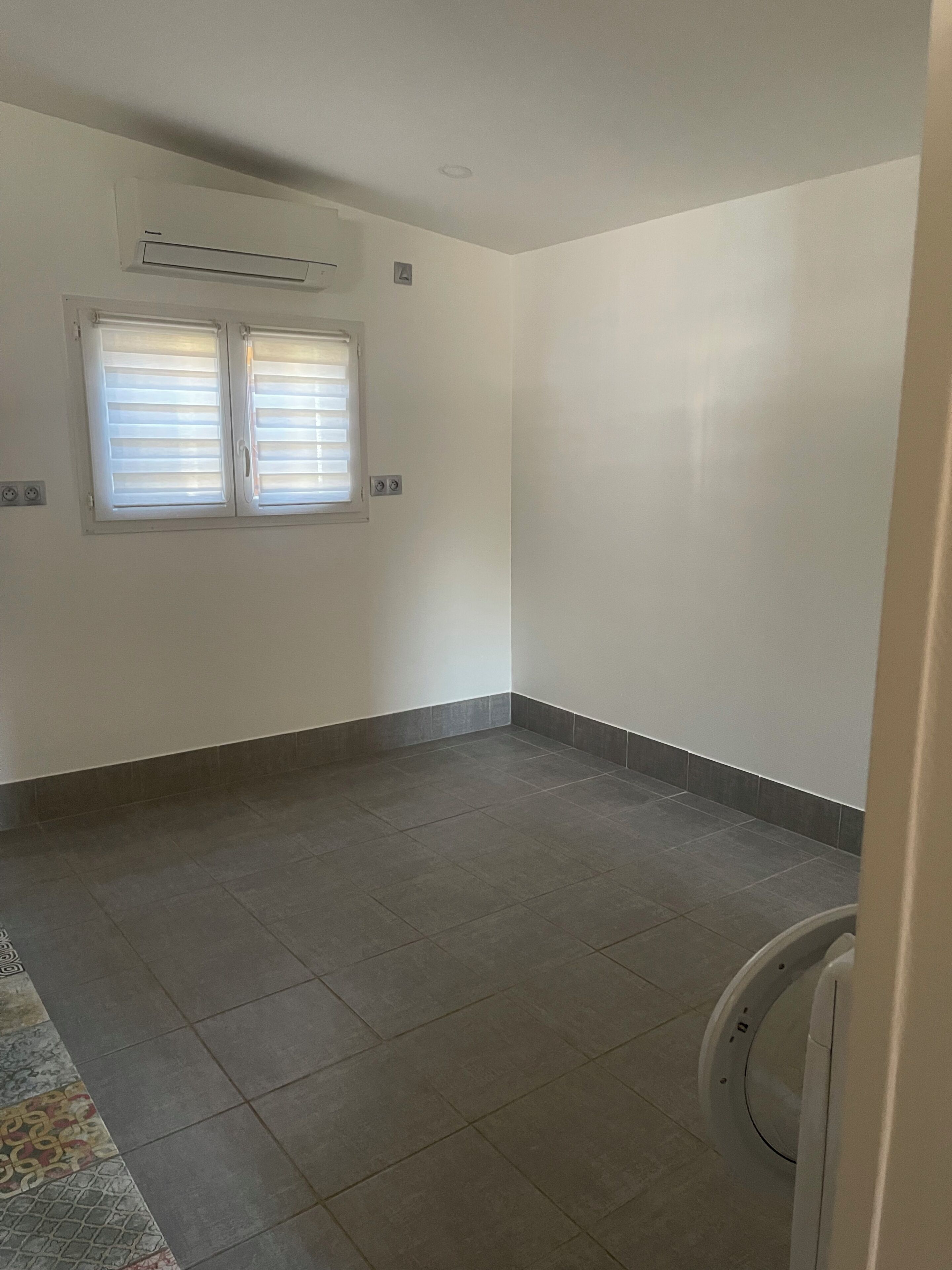 Ein Zimmer mit Fenster, Klimaanlage und Toilette.