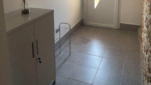 A hallway with a white door, a decorative wall mirror, a metal rack, and a stone wall. - Country house (Malataverne)
