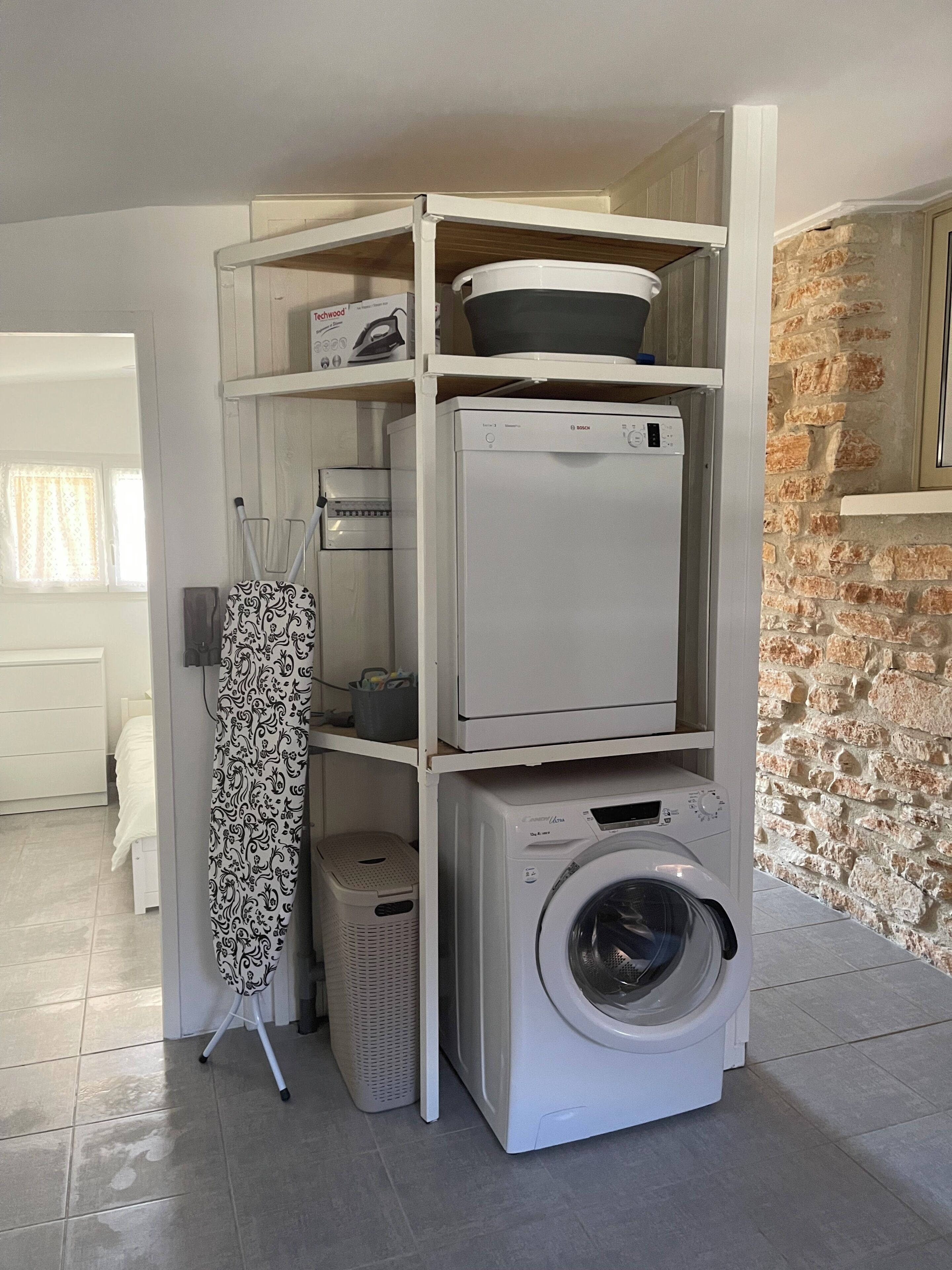 A laundry area with a washing machine, dryer, and ironing board.