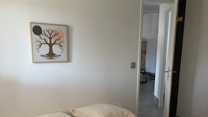 A room with a bed, pillows, a wall-mounted picture, and an open door leading to another room. - Country house (Malataverne)