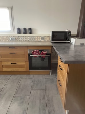 Eine Küche mit Mikrowelle, Backofen und einer Holzküche mit Schubladen.