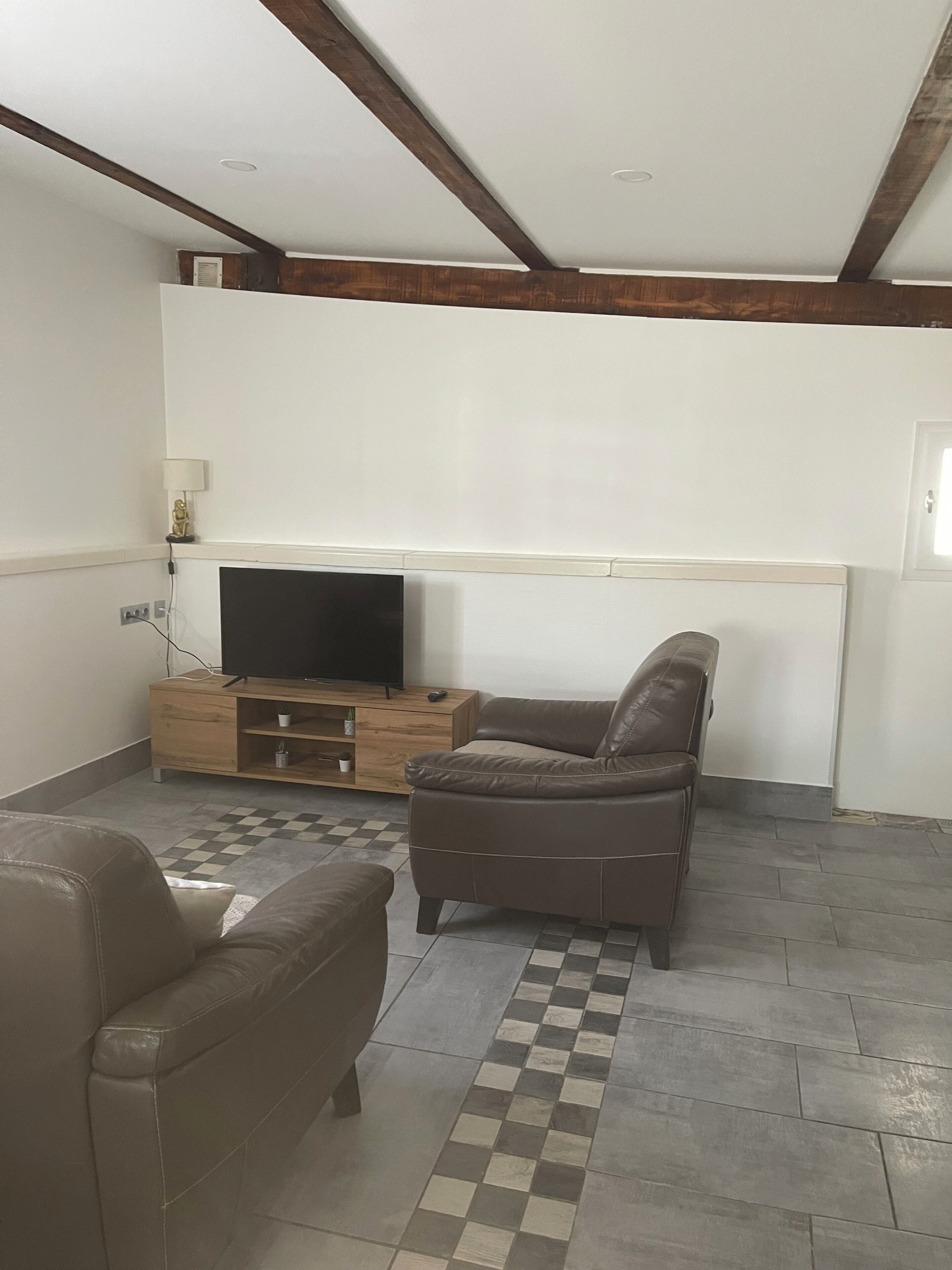 Ein Wohnzimmer mit Fernseher, einer Couch, einem Couchtisch und einem gemusterten Teppich.