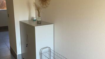 Une pièce comprenant un meuble blanc, une étagère en métal et deux miroirs fixés au mur.
