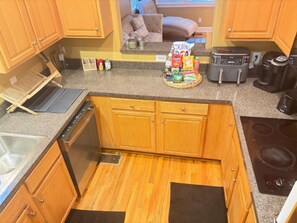 Eine kleine Küche mit Holzausstattung, einem Geschirrspüler, einer Kaffeemaschine und einem Toaster.