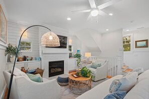 A modern living room with a fireplace, white walls, and a ceiling fan. - Overlooking the 13th tee of the Bald Head Island Club golf course (Bald Head Island)