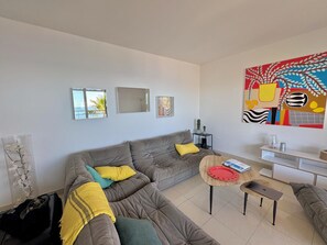Ein Wohnzimmer mit einem grauen Sofa, einem kleinen runden Tisch und einem weißen Schrank.