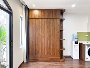 A room with a wooden wardrobe, a water dispenser, and a washing machine. - Hannari Cozy Serviced Apartment (Hanoi)