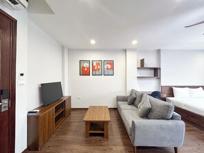 A modern living room with a sofa, a coffee table, a TV, and artwork on the wall. - Hannari Cozy Serviced Apartment (Hanoi)