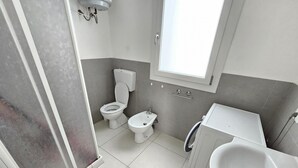 Een badkamer met toilet, bidet en wastafel.