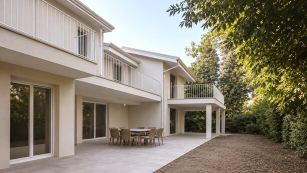 Een modern huis met twee verdiepingen, een terras, een eettafel en stoelen.