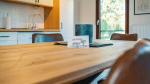 Una mesa de comedor de madera con un cartel que dice 'WELCOME', un jarrón oscuro y una ventana con vista a árboles.