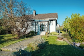 Une maison moderne dotée d’une véranda en verre, d’un chemin en pierre et d’un jardin bien entretenu.