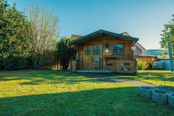 Eine Holzhütte mit Veranda, einem kleinen Garten und Blick auf die umliegende Landschaft.