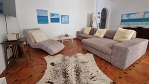 Een woonkamer met een bank, salontafel, vloerkleed en wanddecoratie.