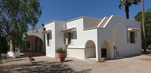 A white building with arched doorways and a small porch area. - Family Villa Mareluna in Lido Marini with a private pool, located near the Ionian Sea (Lido Marini/Com. Salve)