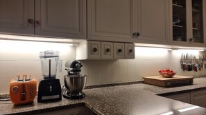 A kitchen with white cabinets, a blender, a mixer, and a fruit bowl on the counter. - Family Villa Mareluna in Lido Marini with a private pool, located near the Ionian Sea (Lido Marini/Com. Salve)