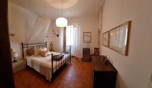 A bedroom with a bed, bedside table, lamp, curtains, and a framed picture on the wall. - Family Villa Mareluna in Lido Marini with a private pool, located near the Ionian Sea (Lido Marini/Com. Salve)