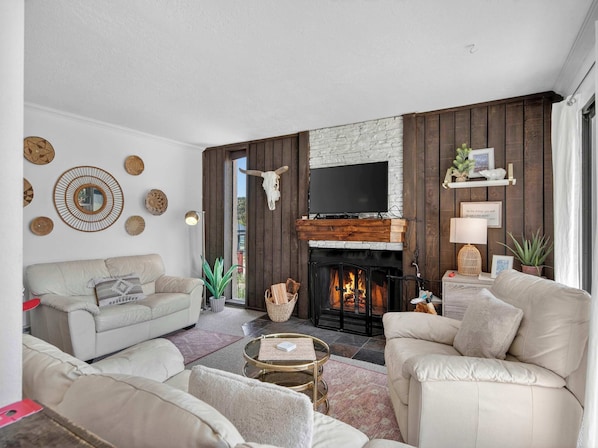 Ein Wohnzimmer mit Kamin, Sofas, einem Fernseher und Wanddekoration.