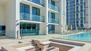 Een modern hotel met een zwembad, terras en meerdere balkons.