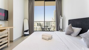 Een moderne hotelkamer met een groot bed, een bureau, een stoel en een aan de muur bevestigde televisie.