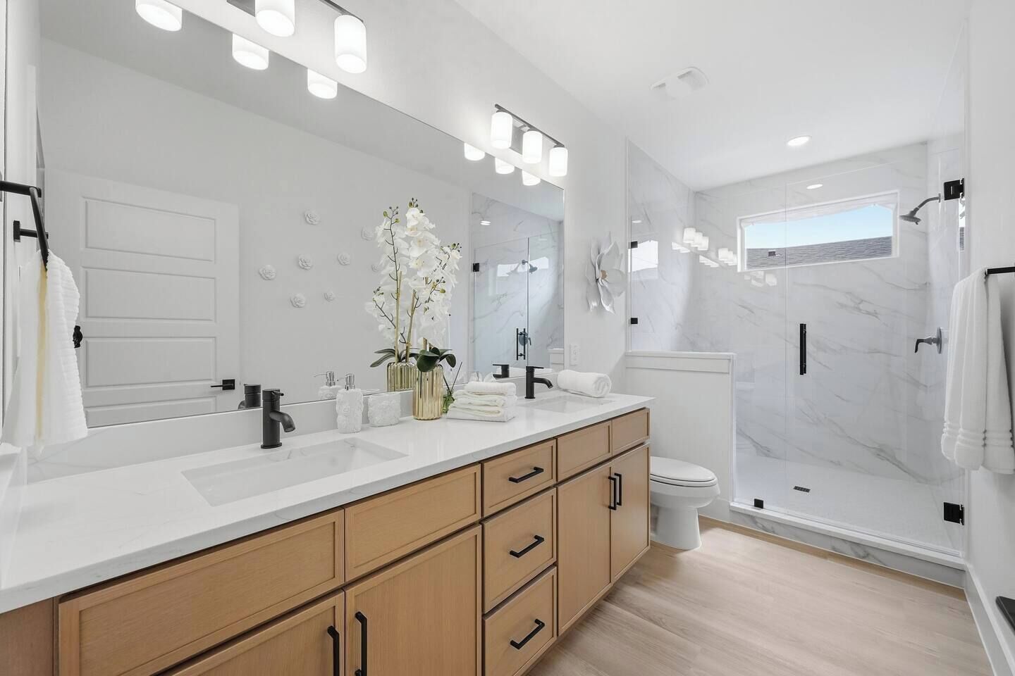 A modern bathroom with a large mirror, a shower, and a toilet.