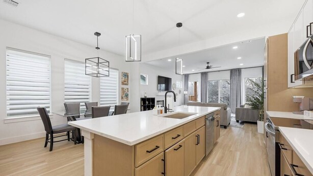 Une cuisine moderne dotée d’un grand îlot central, de meubles en bois et de luminaires suspendus.
