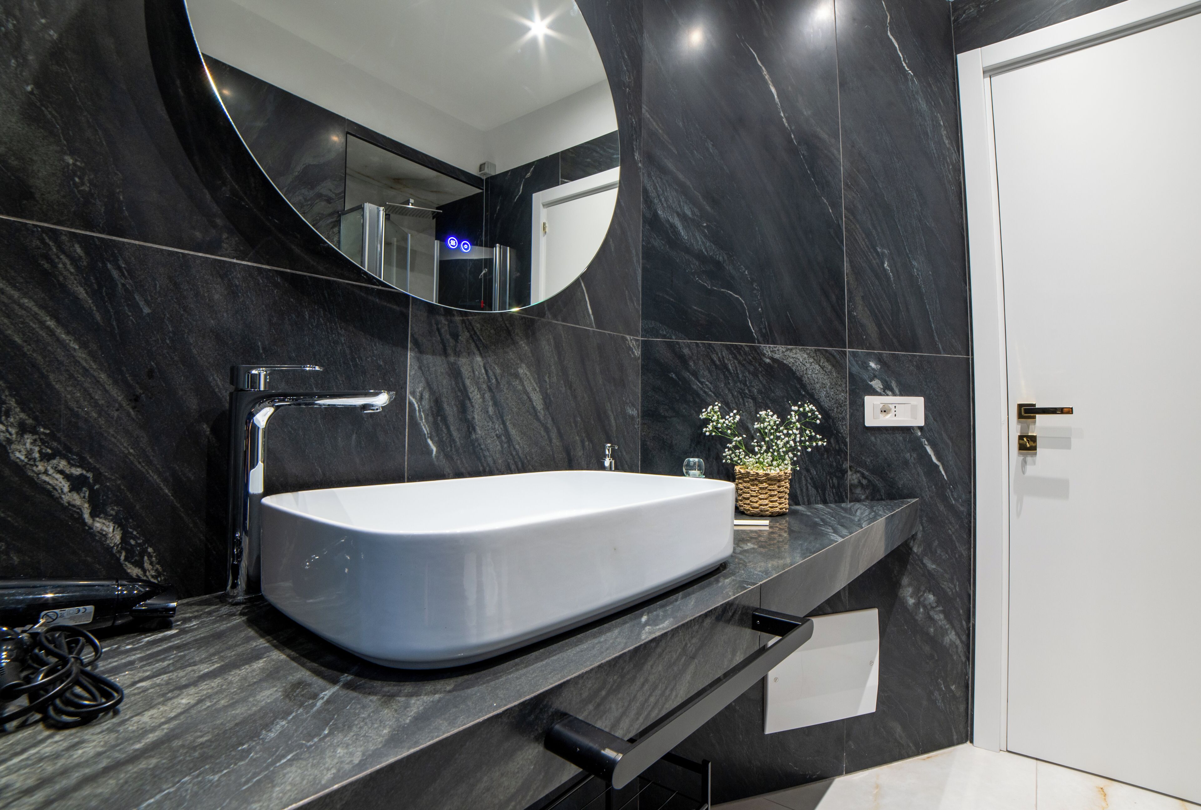 A modern bathroom with a large oval sink, a mirror, and a potted plant.