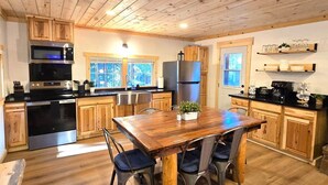 Una cocina con armarios de madera, un refrigerador de acero inoxidable, un microondas y una mesa de comedor con sillas.