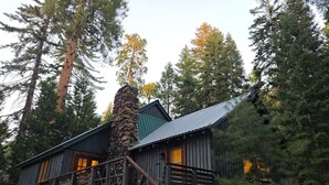 Una cabaña rústica con chimenea de piedra, fachada de madera y un balcón con una bicicleta.