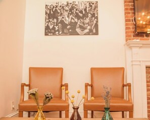 Quarto com duas poltronas de couro, uma mesa com vasos e uma fotografia preto e branco na parede.