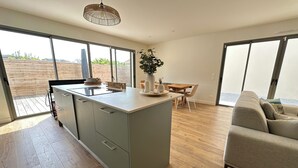 A modern kitchen with a central island, wooden flooring, and large windows. - Comfortable villa 2 minutes from the beach with large terrace, 4 bedrooms (Biscarrosse)