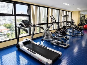 Ein Fitnessraum mit Laufbändern, Crosstrainern und Gewichten.