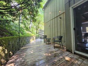 A wooden deck with chairs, a wall with string lights, and a glass door. - Haus Edelweiss • Near Wineries & Skiing (Banner Elk)