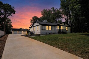 Ein zweistöckiges Haus mit Garage, Veranda und einem gepflegten Rasen.