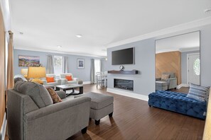 Ein modernes Wohnzimmer mit einer Couch, einem Hocker und einer blauen gepolsterten Bank.