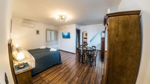 A bedroom with a bed, bedside table, lamp, and a TV on the wall. - Paladini al Casale (Piazza Armerina)