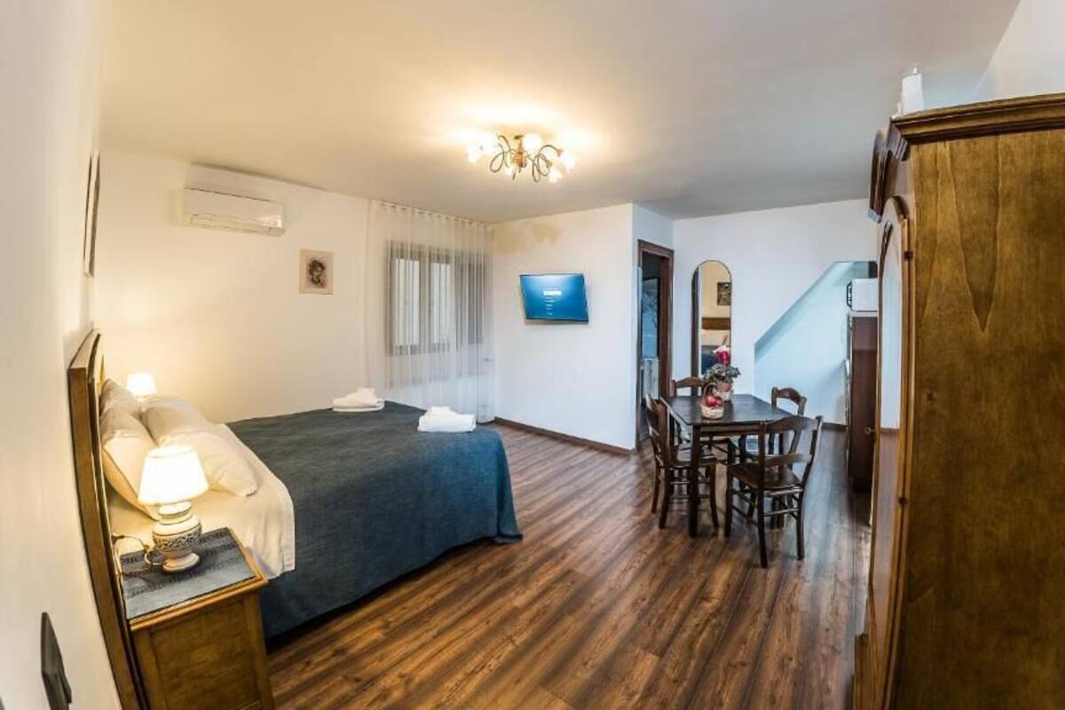 A bedroom with a bed, bedside table, lamp, and a TV on the wall.