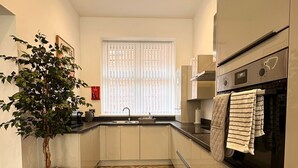 Una cocina moderna con suelo de espiga, horno empotrado y una planta en maceta.