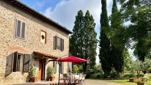 A stone building with a patio, outdoor furniture, and a red umbrella.