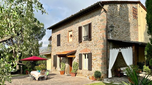 Un edificio in pietra con un patio, posti a sedere all'aperto e piante in vaso.