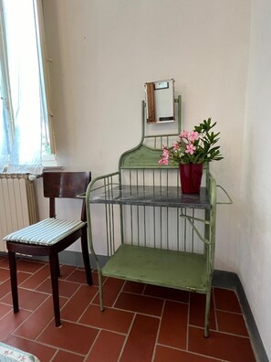 A corner room with a metal chair, a small table, a potted plant, and a radiator. - Tuscan country house (Larciano)