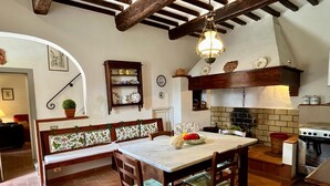 Una cucina rustica con un tavolo in marmo, sedie di legno, una panca e un lampadario.