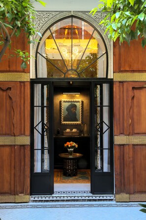 An entrance with a large arched doorway, a mirror, and a small table with flowers. - The riad saeed : A luxury riad in the heart of Marrakech Medina (Marrakesh)