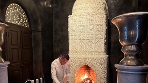 A dining area with a fireplace, a table set for two, and a black and white striped bench. - The riad saeed : A luxury riad in the heart of Marrakech Medina (Marrakesh)